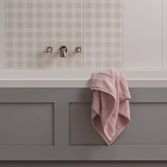 A soft pink textured towel draped over a gray bathtub edge nova scotia middleton 60x30cm bath towel