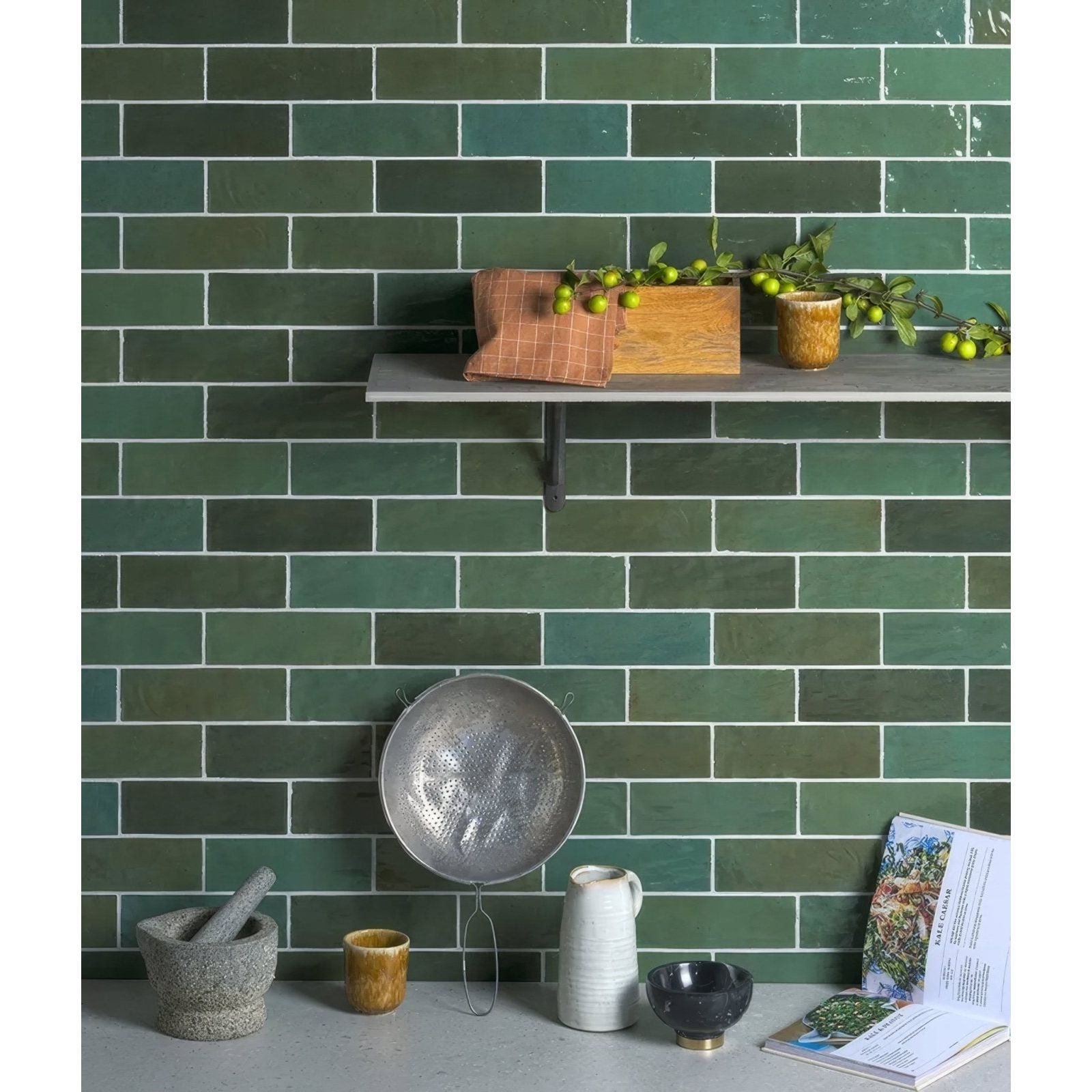 A round metallic colander with textured surface and handles in oasis ceramic green gloss finish