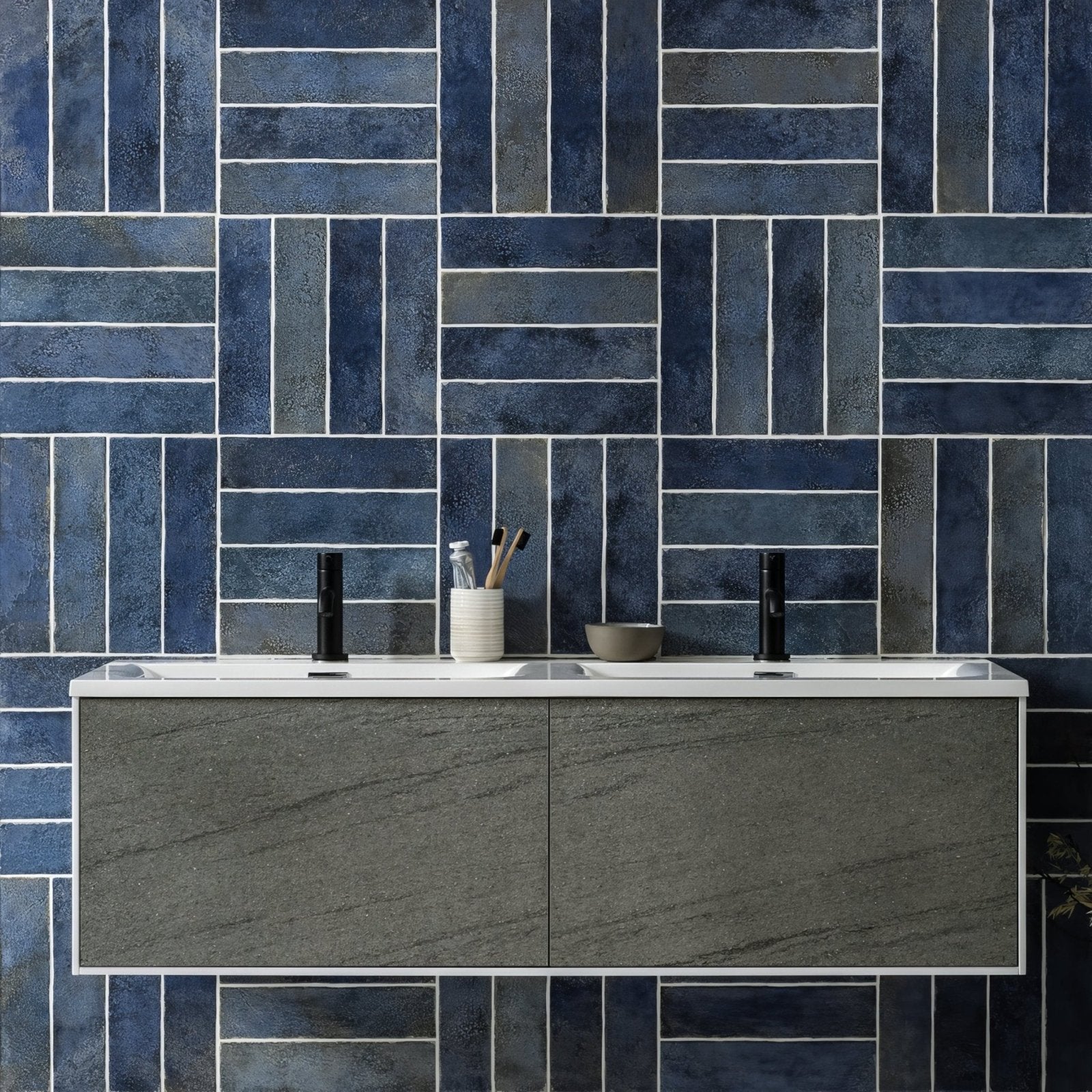 Modern gray stone-look vanity with white countertop and two black faucets in oken brick blue product line