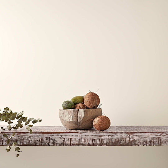 Weathered wooden bowl filled with coconuts and limes representing old cream natural tropical ingredients