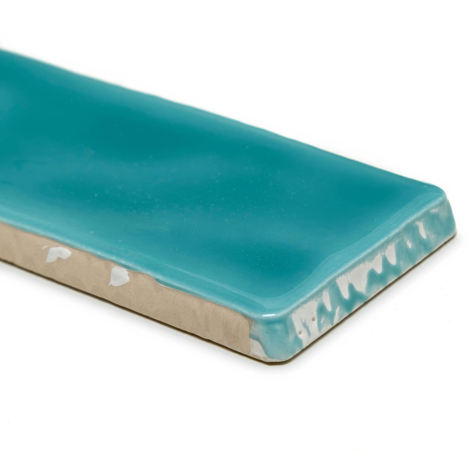 A glossy turquoise ceramic onda aquamarine wall tile with a textured edge and visible beige backing shown from the back