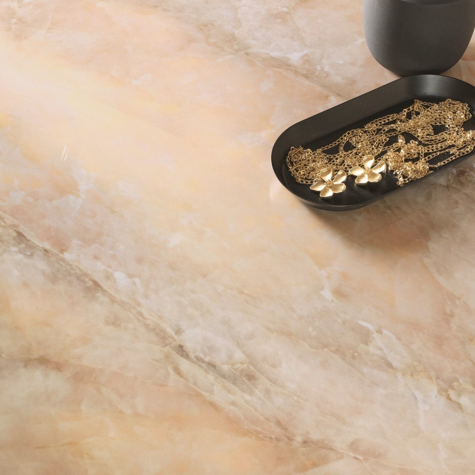 Onyx Copper Polished amber marble-effect tiles with gold pendant necklaces on a tray