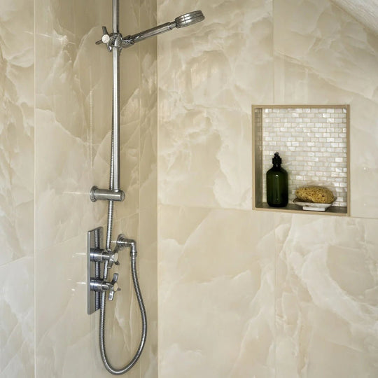 Onyx Ivory Matt Marble Effect Tile 60 x 120 white marble-effect tiles with a chrome showerhead