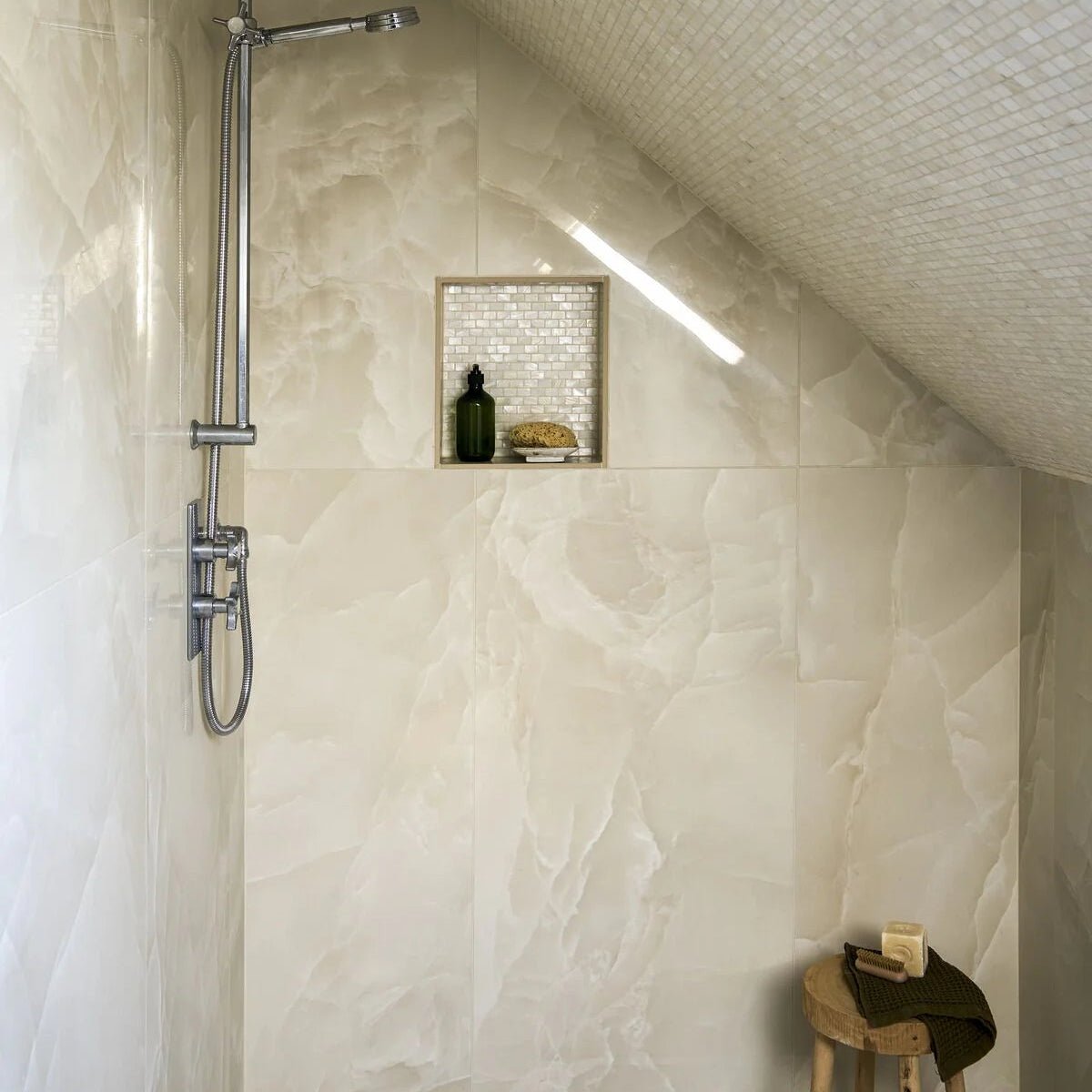 Onyx ivory polished marble effect tile 60 x 120 with a sleek chrome finished showerhead with elongated spout and curved nozzle