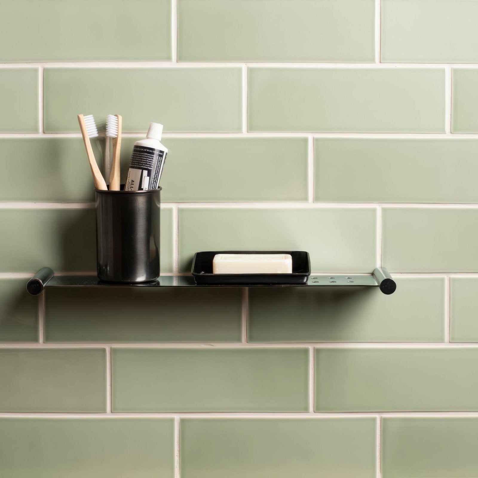 Black metal shelf with rounded ends and soap dish on the right side in brick tile orford design