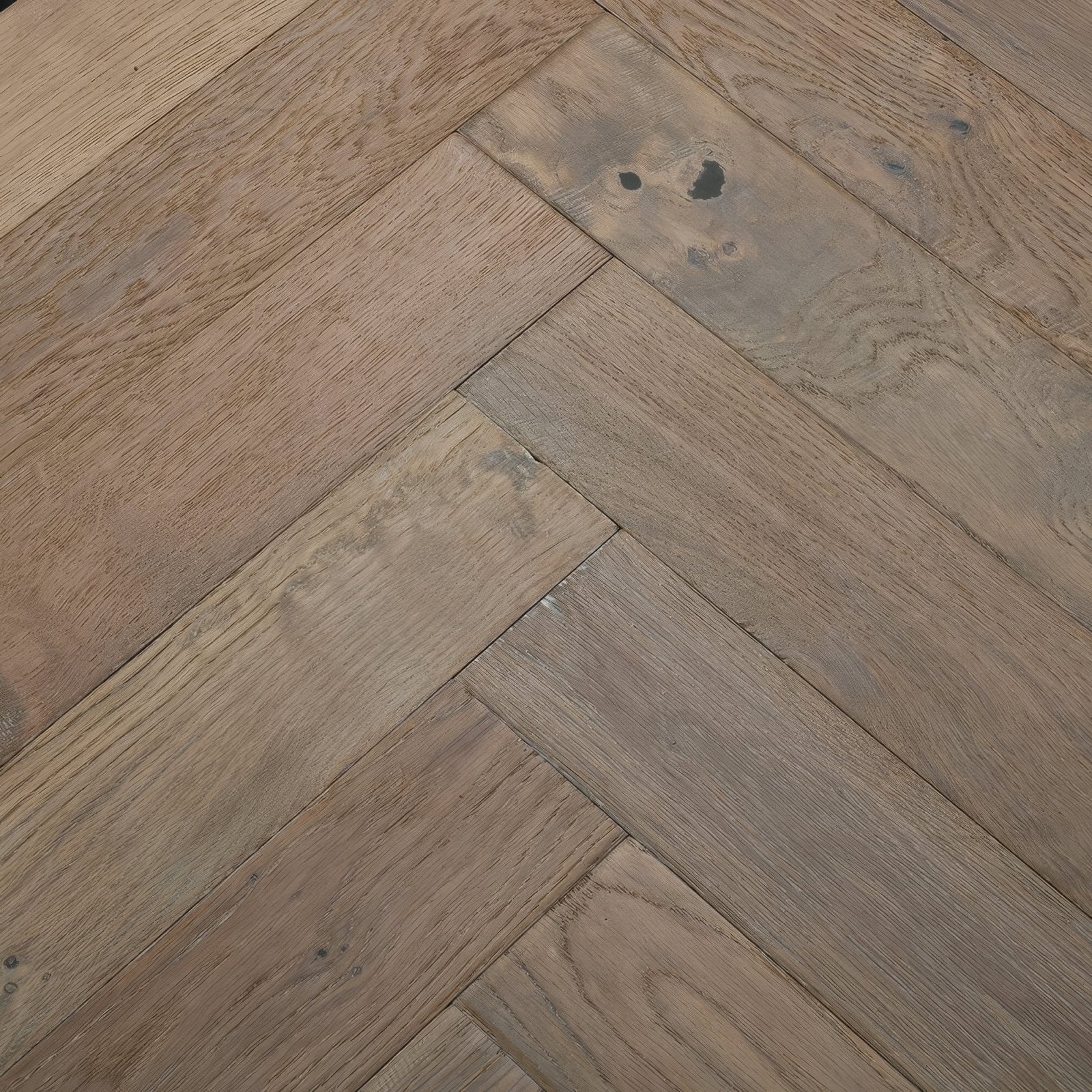 Orkney Pewter Oak dark brown hardwood floor planks arranged in herringbone pattern with natural wood grain and subtle imperfections
