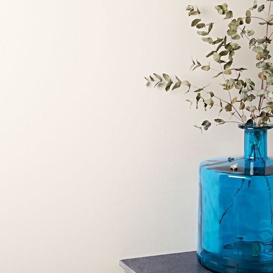 Oyster translucent cobalt blue glass vase with rounded body and narrow neck holding dried eucalyptus branches