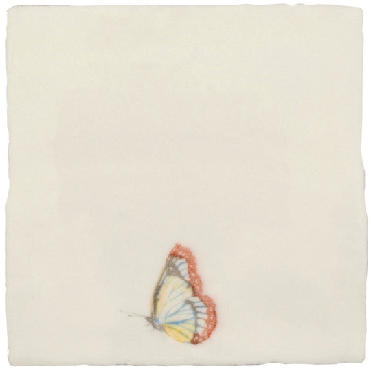 A delicate hand-painted butterfly with translucent soft yellow and white wings rests on a pastel cotton ceramic tile