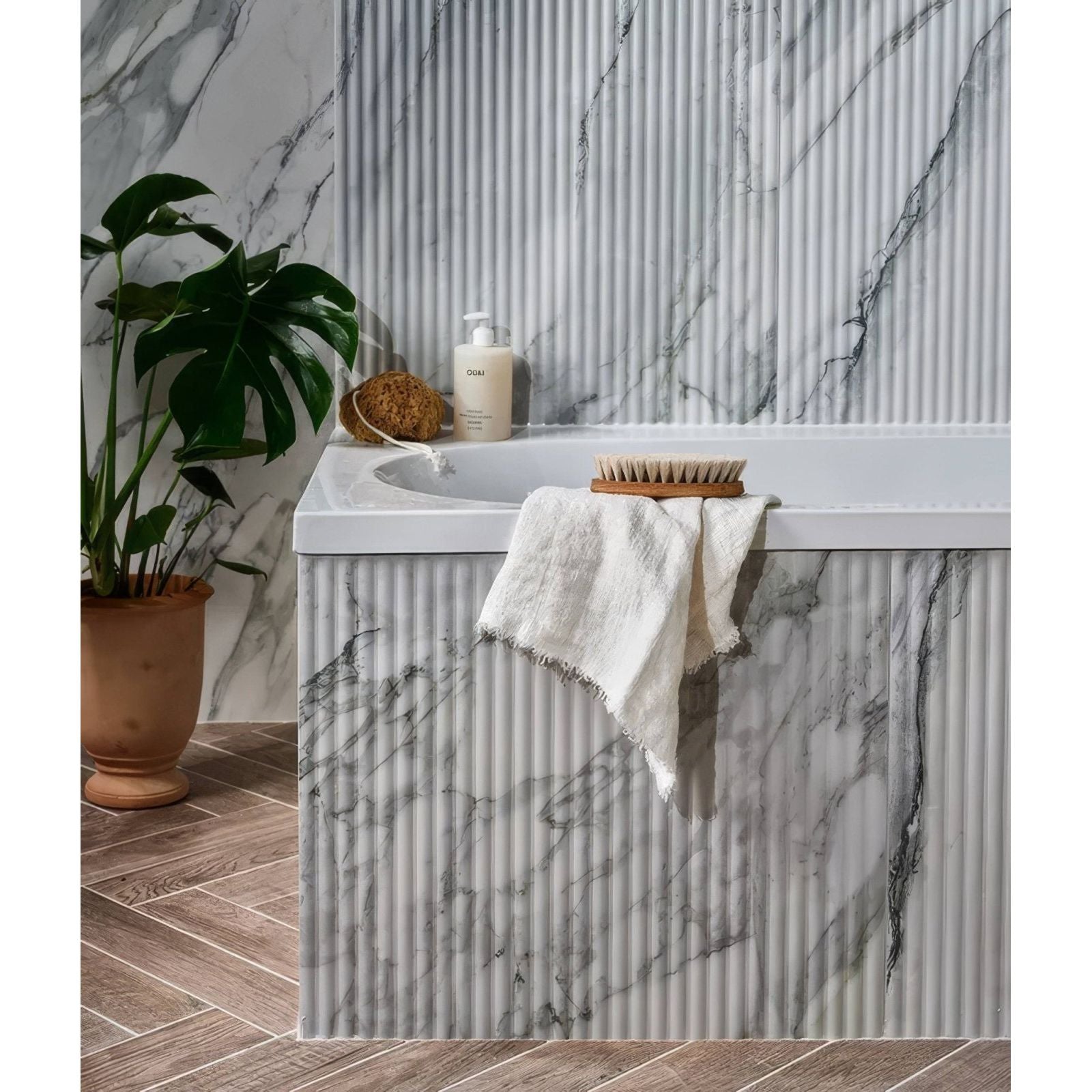 Palm Springs Porcelain Cerulean Fluted white and grey fluted marble-effect tiles with a bathtub and towel
