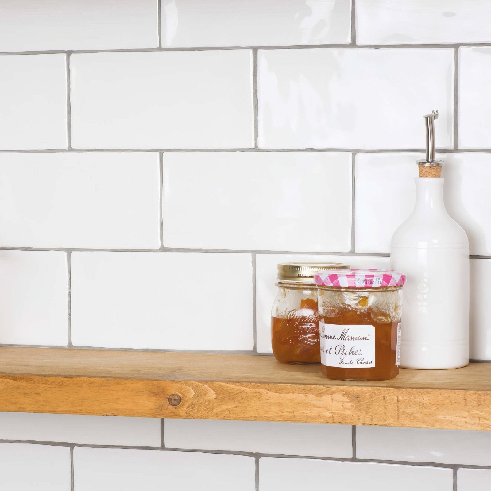 A clear glass jar with a pink and white checkered lid filled with amber-colored sweet peach jam for papyrus brick tile use