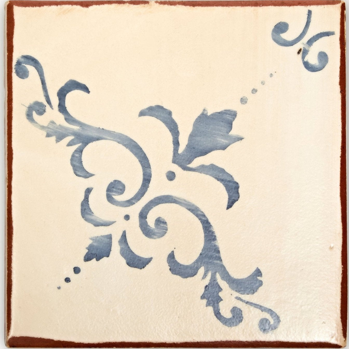 Cream-colored ceramic paris isabelle terracotta tile with rustic brown border and blue floral scrollwork design