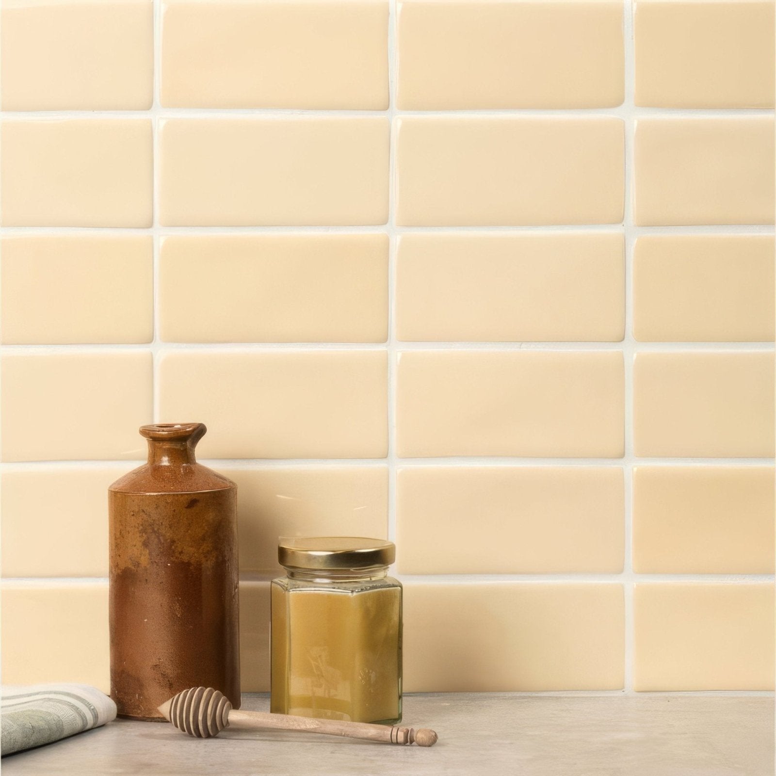 Cream-colored rectangular ceramic peridot half tiles with white grout form a smooth uniform backsplash surface
