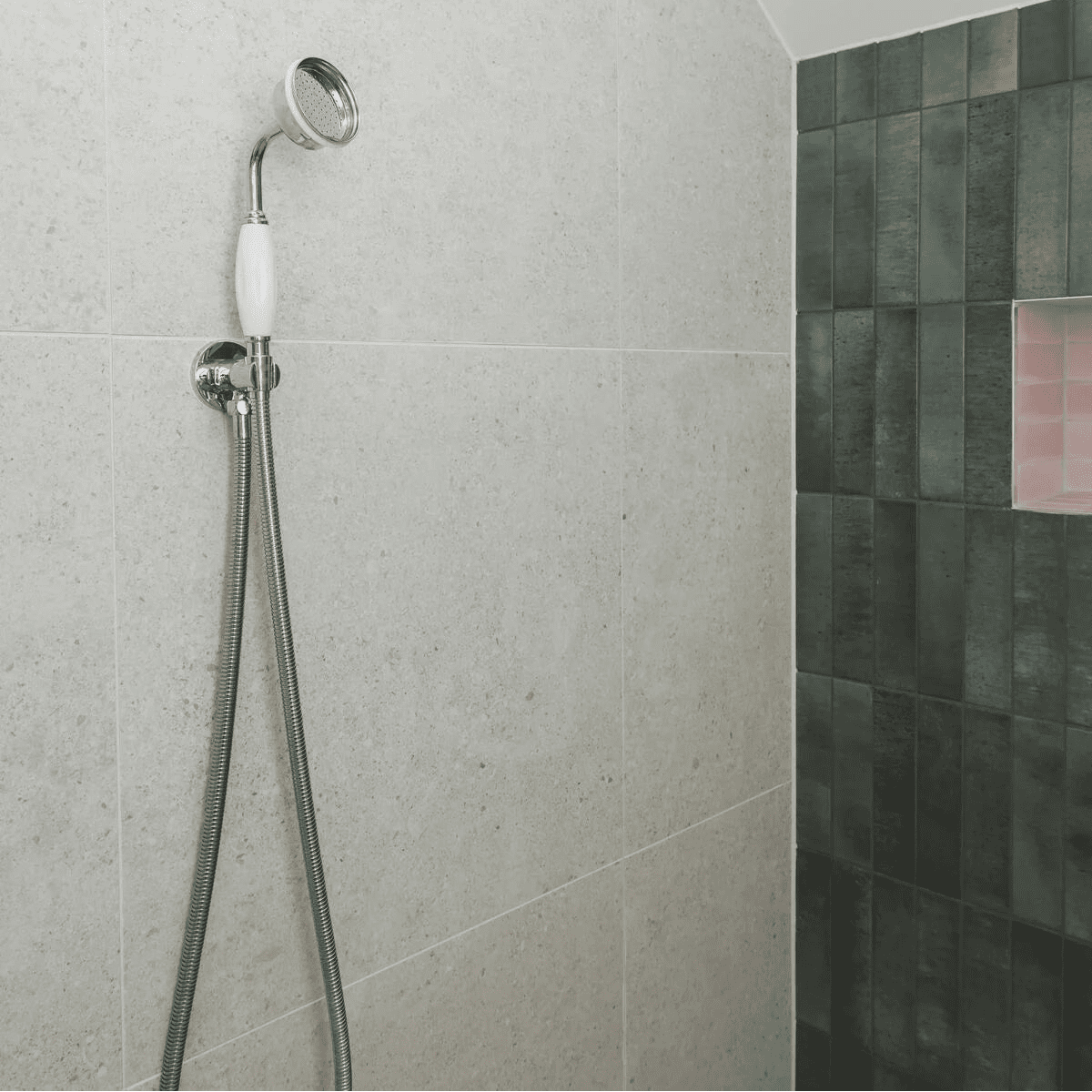 Chrome finished showerhead with white ceramic handle and flexible metal hose mounted on tiled wall for piazza bone 60 x 60cm