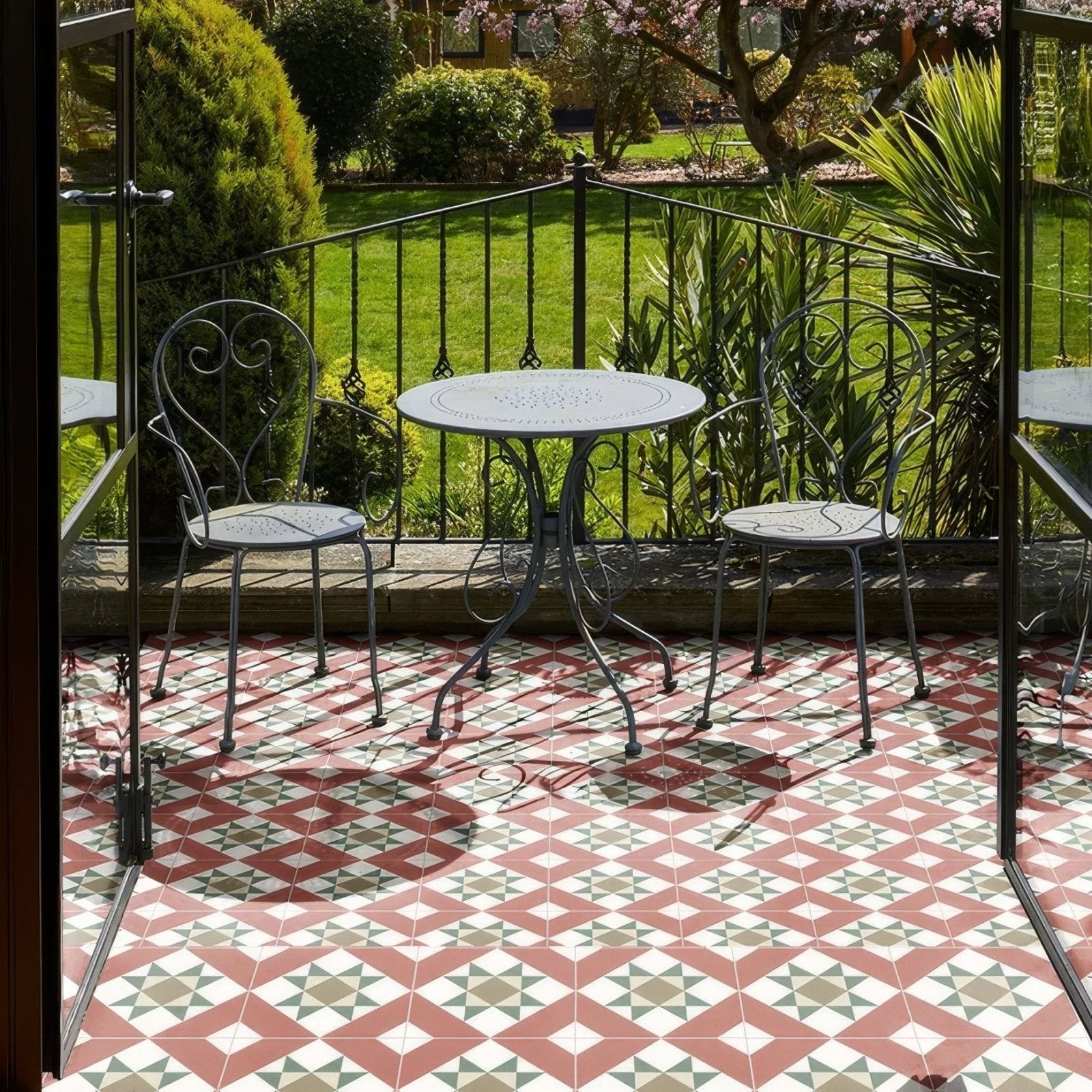 Black wrought iron Brompton porcelain Clarence patio table with ornate scrollwork legs and round perforated tabletop