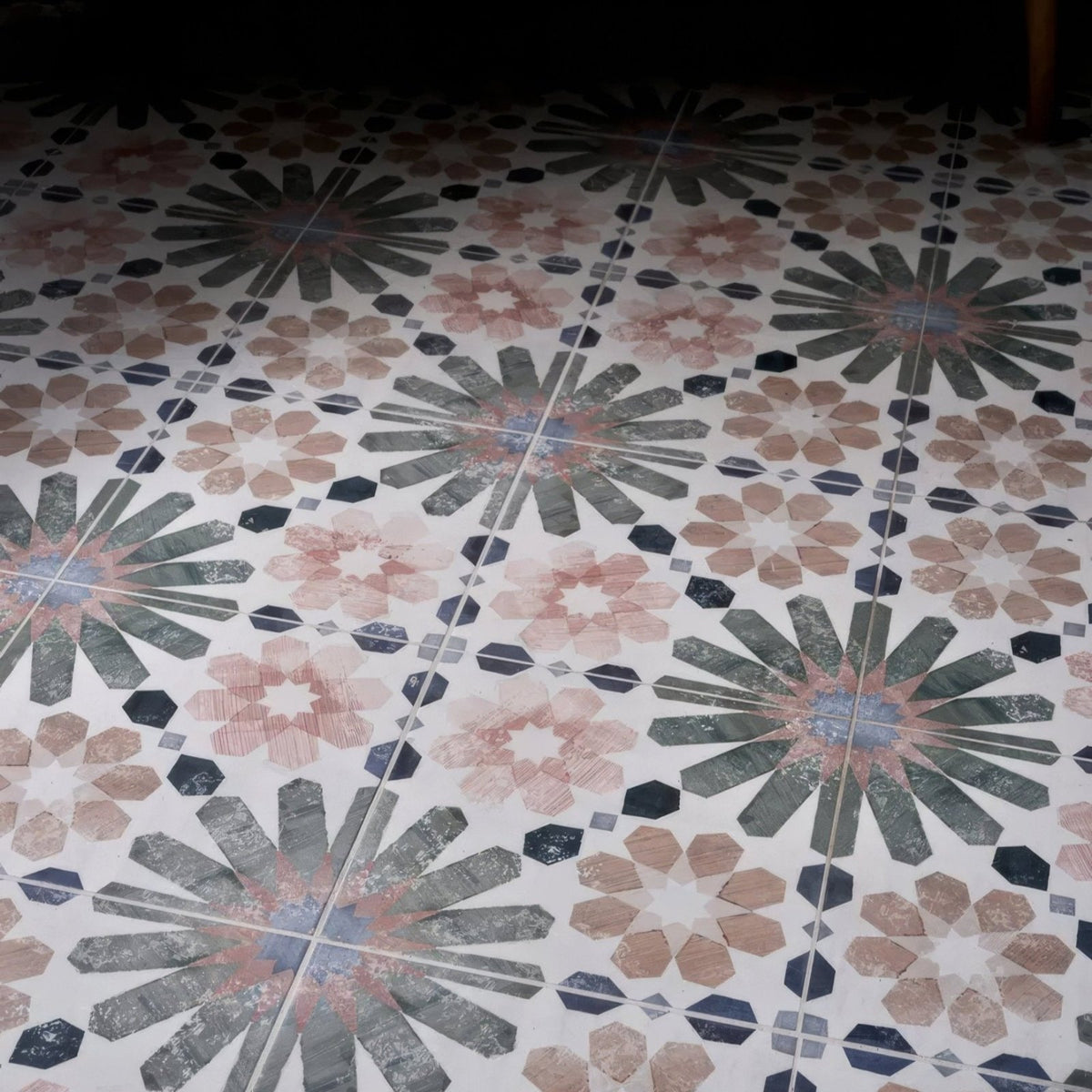 Levante ceramic matt patterned floor tiles with repeating floral design in muted pink gray and black on white background