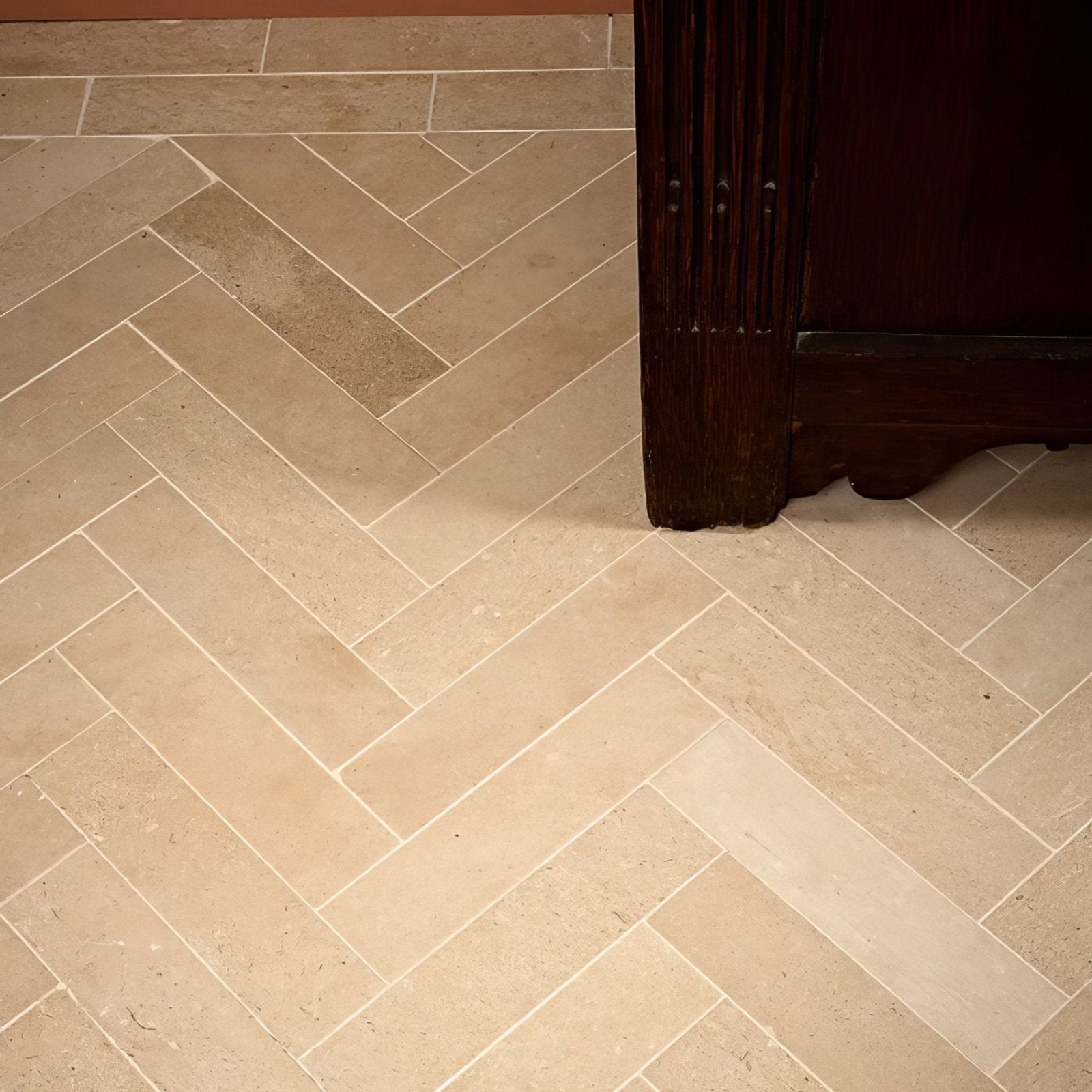 Beige stone tiles in a honed herringbone parquet pattern made of portland limestone for flooring use