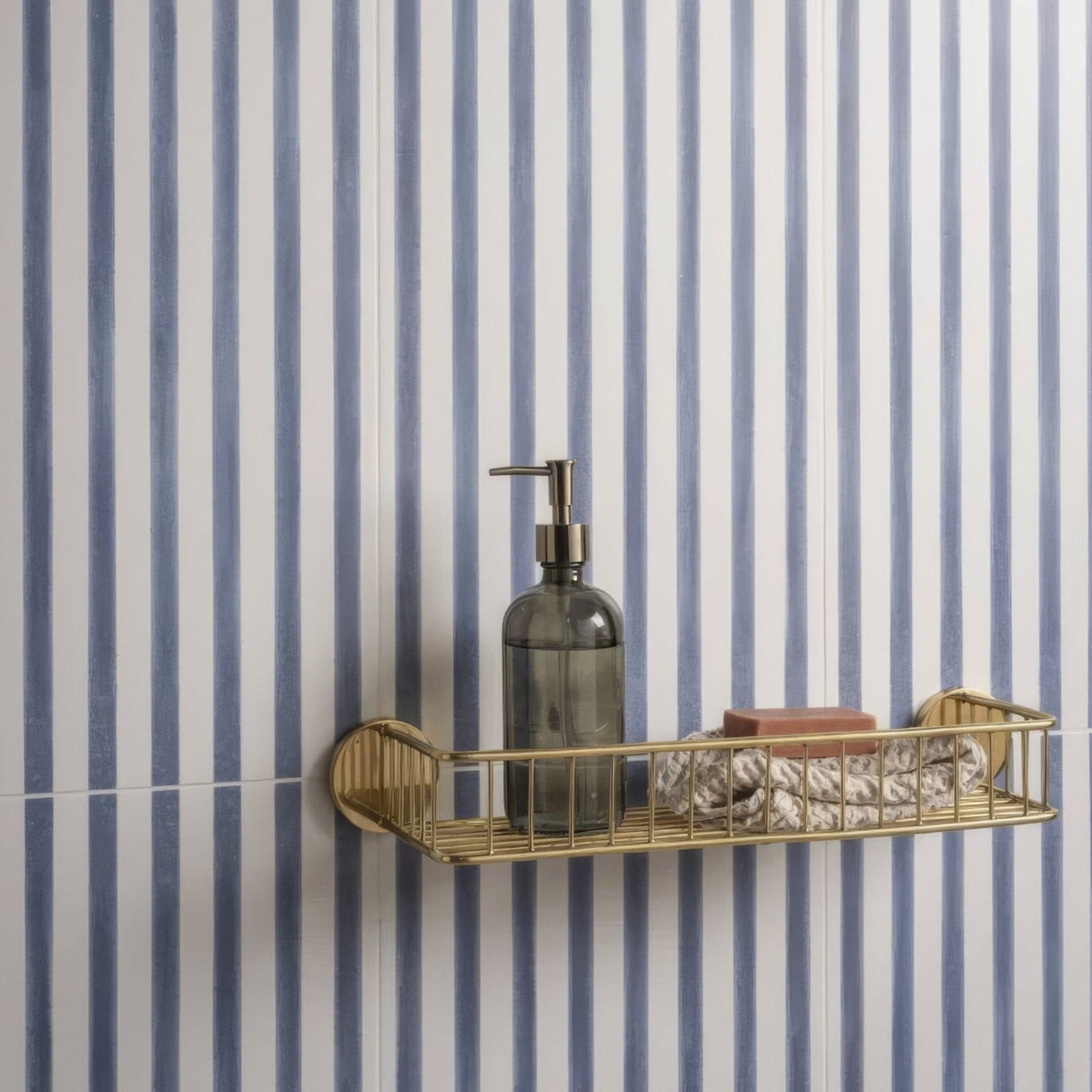 Promenade Brighton 60x30cm gold-toned wire shower caddy with a modern design holding a dark glass soap dispenser and towels
