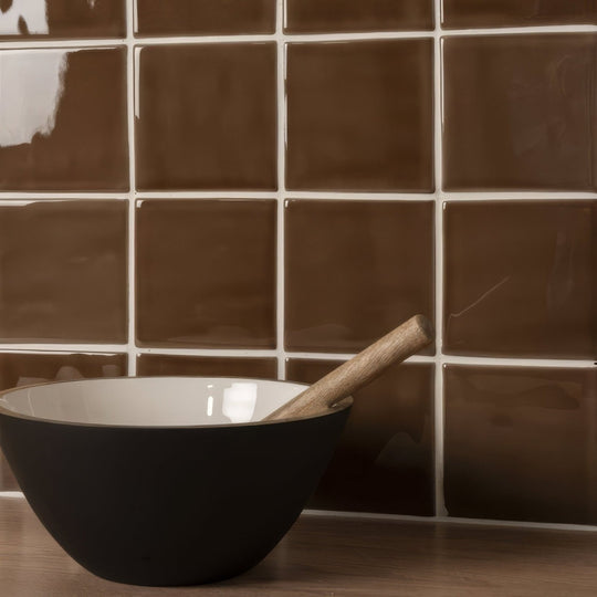 Black ceramic bowl with white interior holding wooden pestle for use with putty field tile products