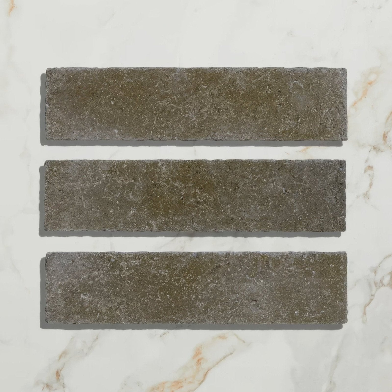 Three rectangular gray reform composite stone tiles with textured natural surface in tumbled khaki finish