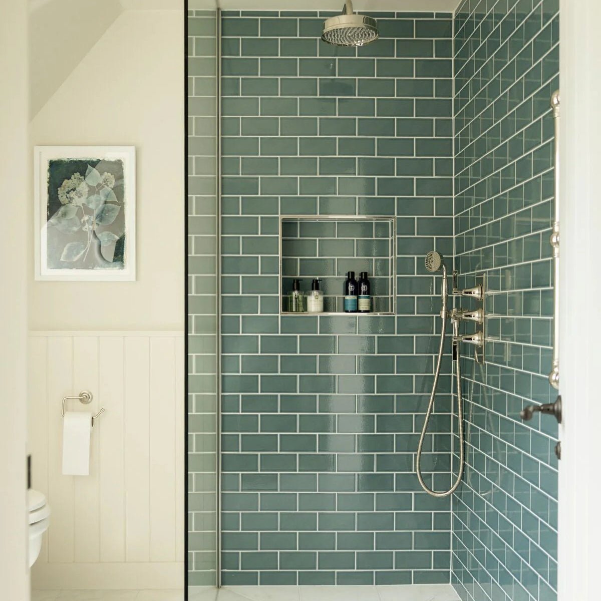 The retro metro green park glazed tile features sleek glossy teal subway tiles with a modern metallic finish in a shower