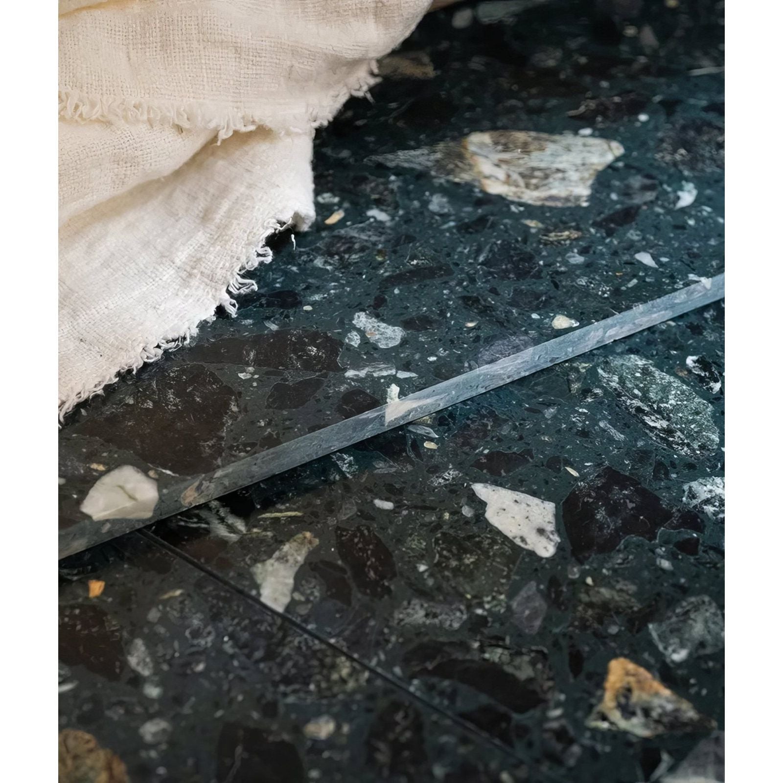 A sleek dark green rialto terrazzo foscari honed tile with white and black stone speckles