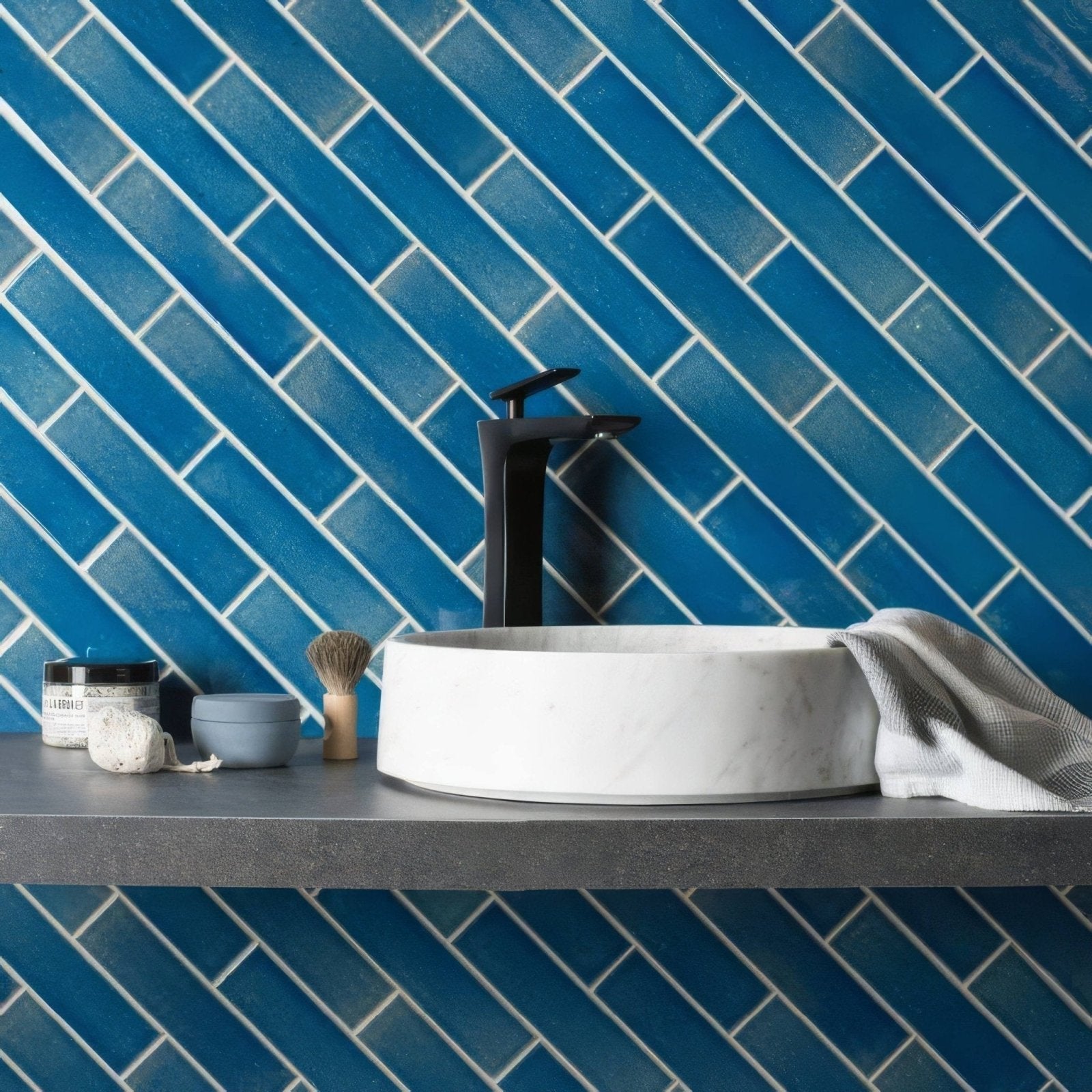 White marble vessel sink with a sleek black faucet against vibrant blue rockpool brick tile backsplash