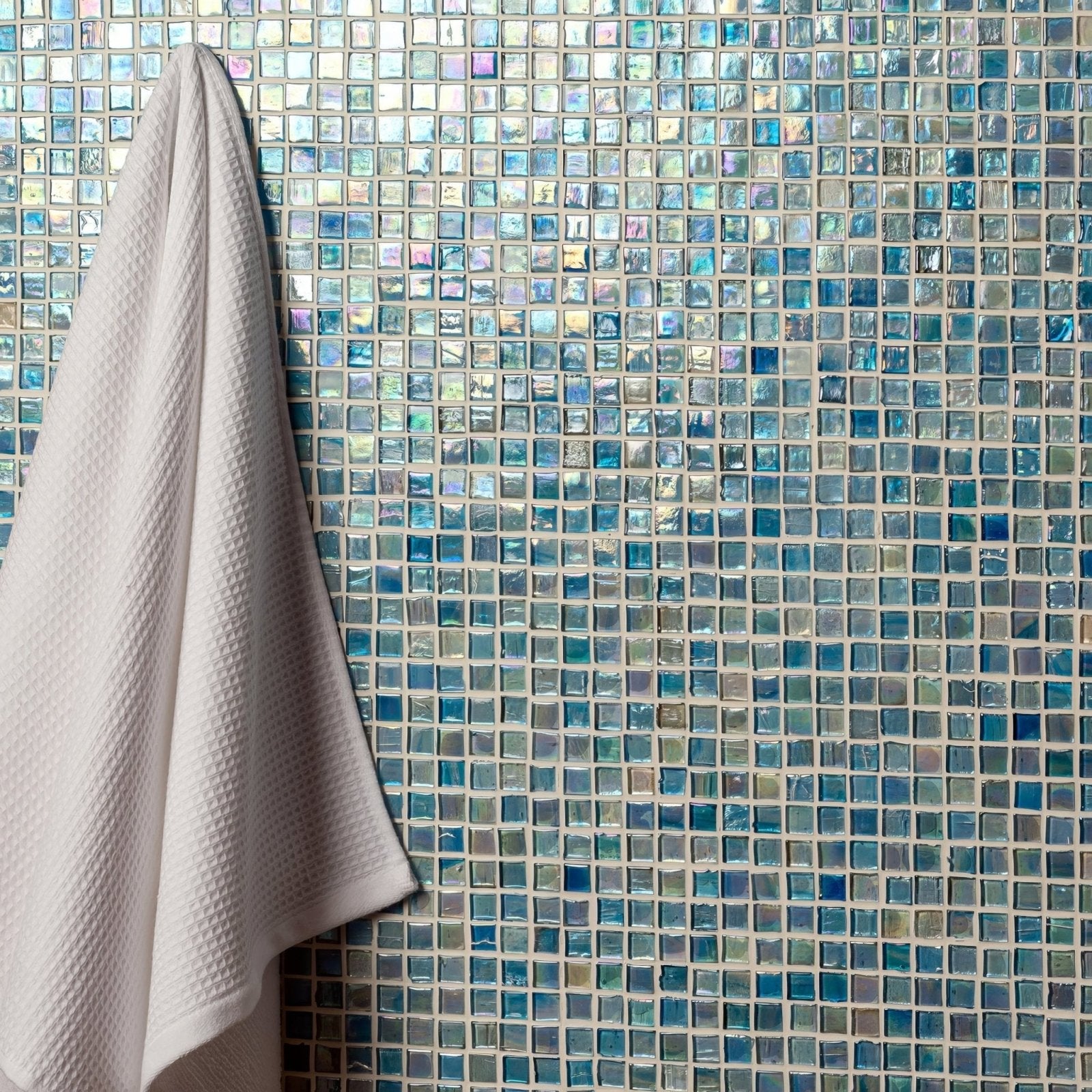 Safira Film Faced Mosaic 15mm iridescent blue glass mosaic with an off-white towel