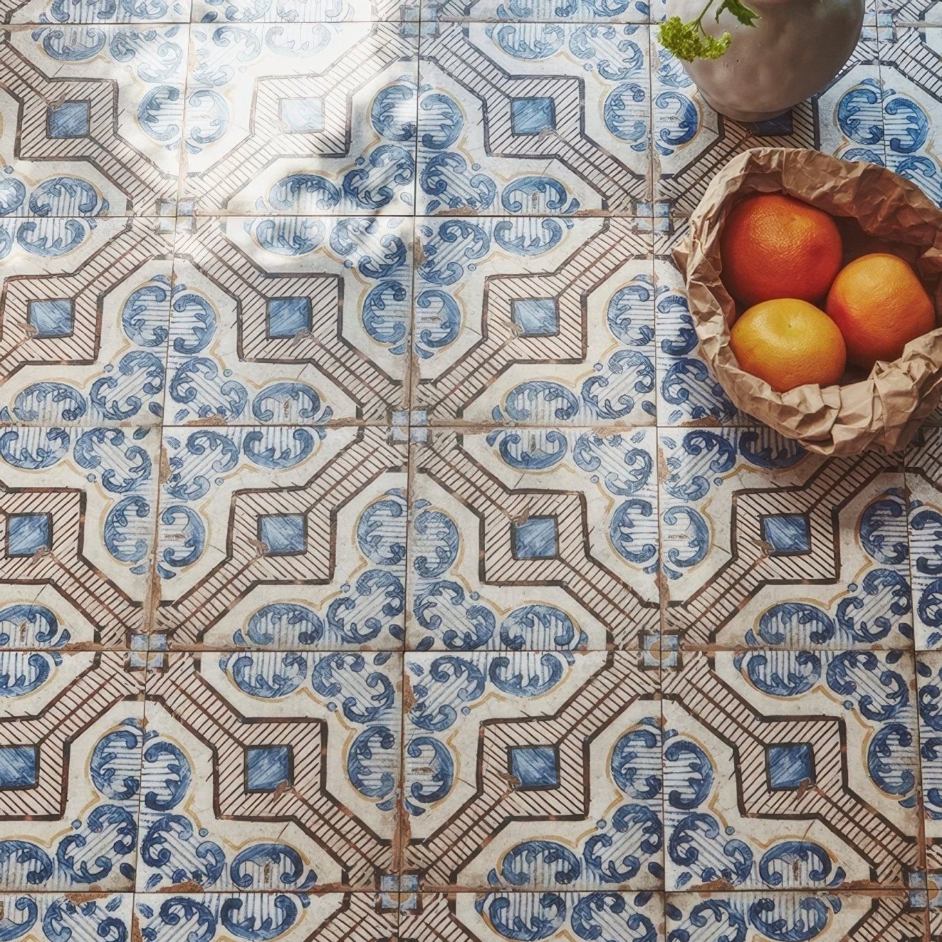 A sardinia porcelain gioia basket lined with brown paper holding three vibrant orange citrus fruits