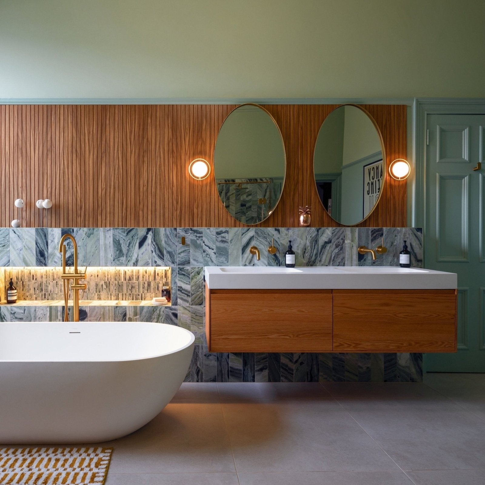 Modern floating wooden vanity with white countertop and gold fixtures displayed on seaspray green marble tile 10 x 30cm