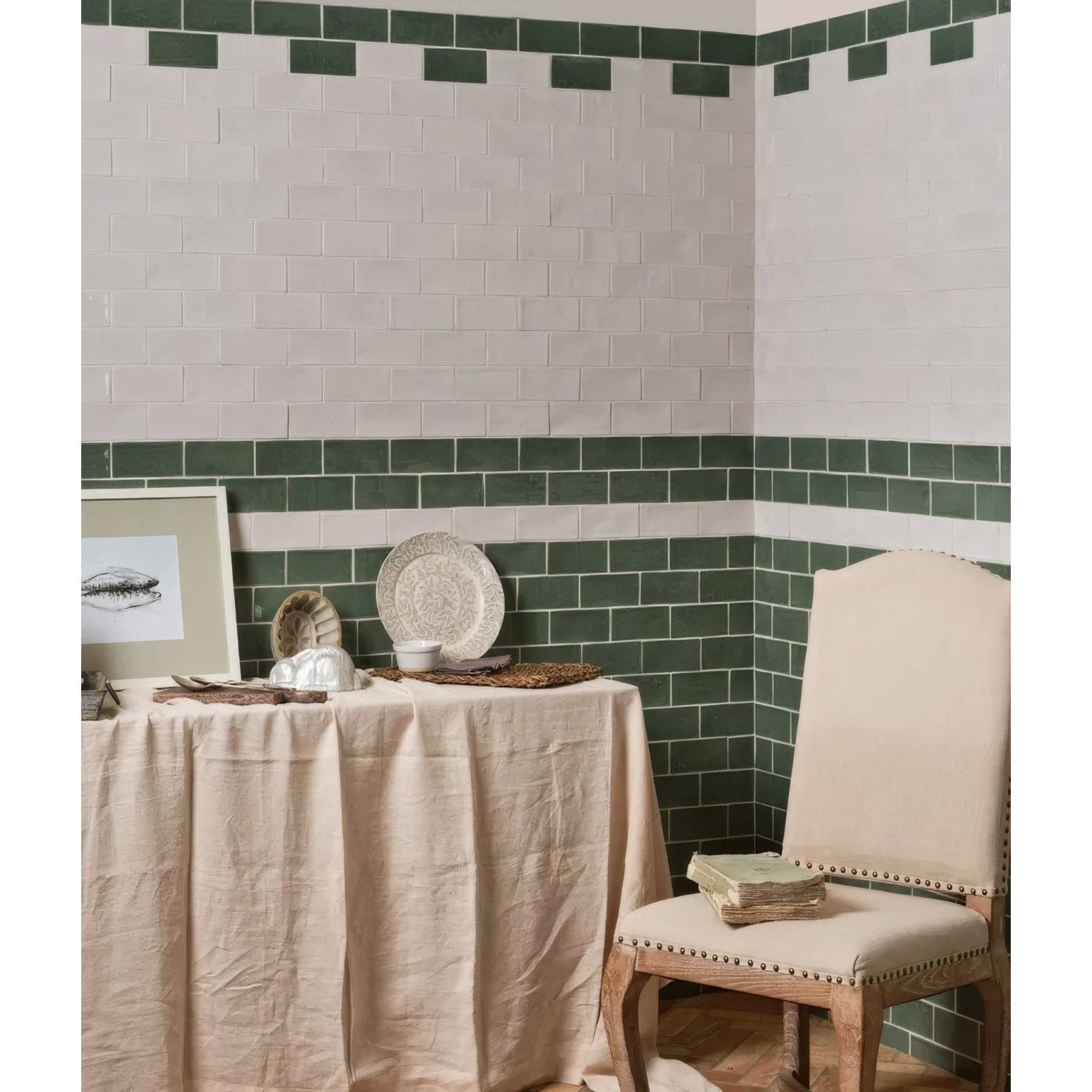 A cream-colored upholstered chair with wooden legs and nailhead trim featured in Seaton Ceramic sea cabbage design
