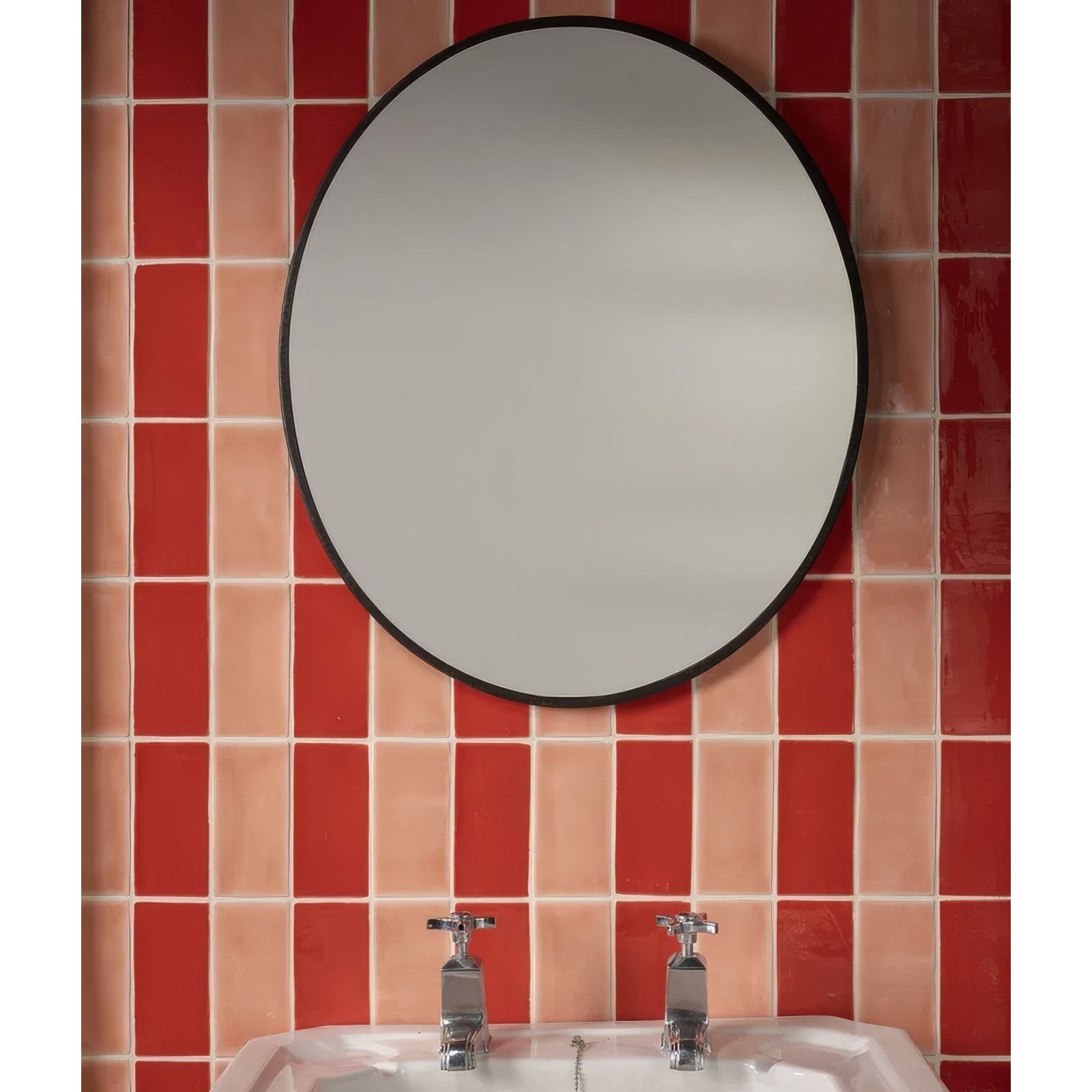 Seaton ceramic shrimp circular mirror with sleek black frame mounted above sink on vibrant red and peach tiled wall