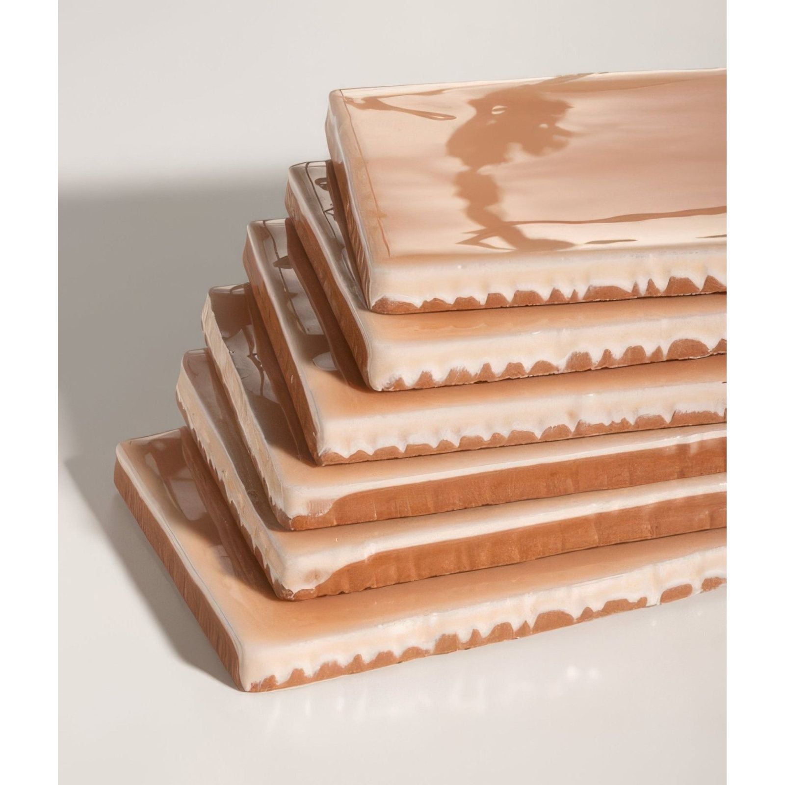 Stack of seaton ceramic shrimp terracotta tiles with cream-colored glaze and textured uneven edges
