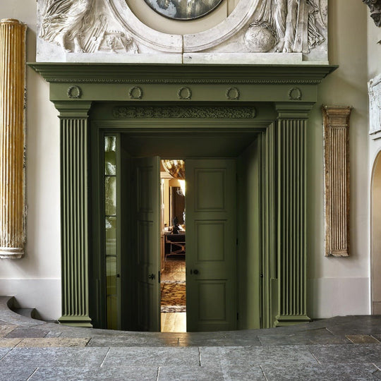 Olive-green painted wooden doorframe selva with fluted columns and ornate carved detailing above