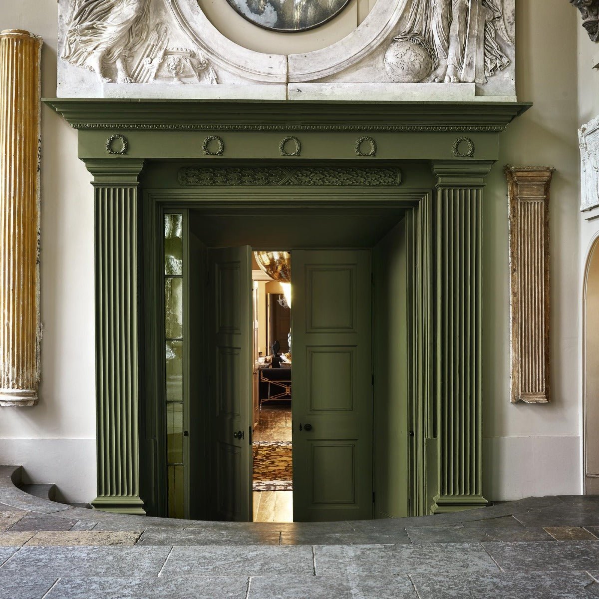 Olive-green painted wooden doorframe selva with fluted columns and ornate carved detailing above