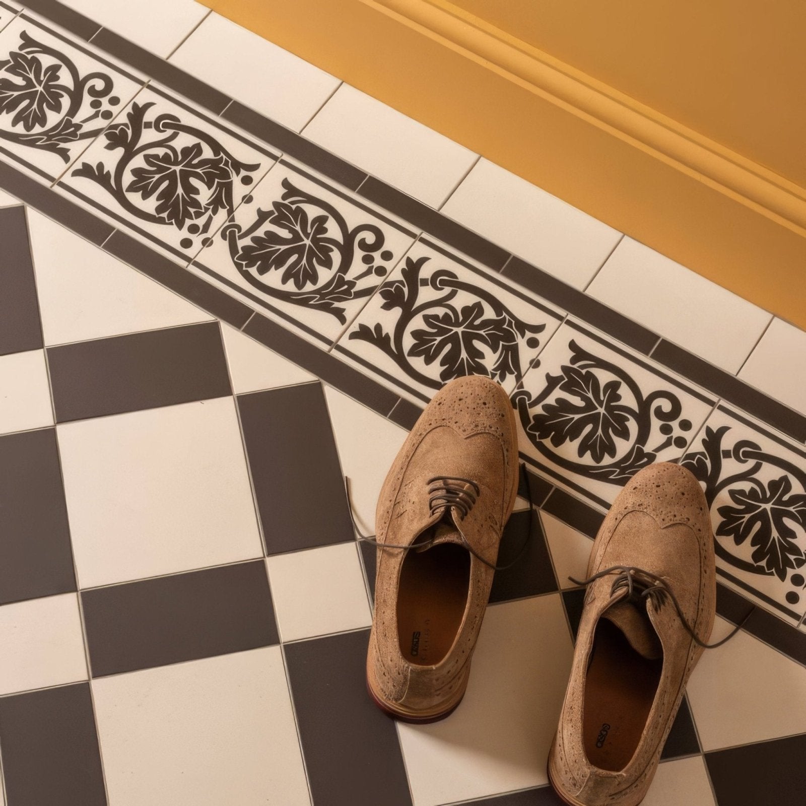 A pair of tan suede brogue dress shoes with dark laces and wingtip design on shaftesbury 2 tile border black on dover white