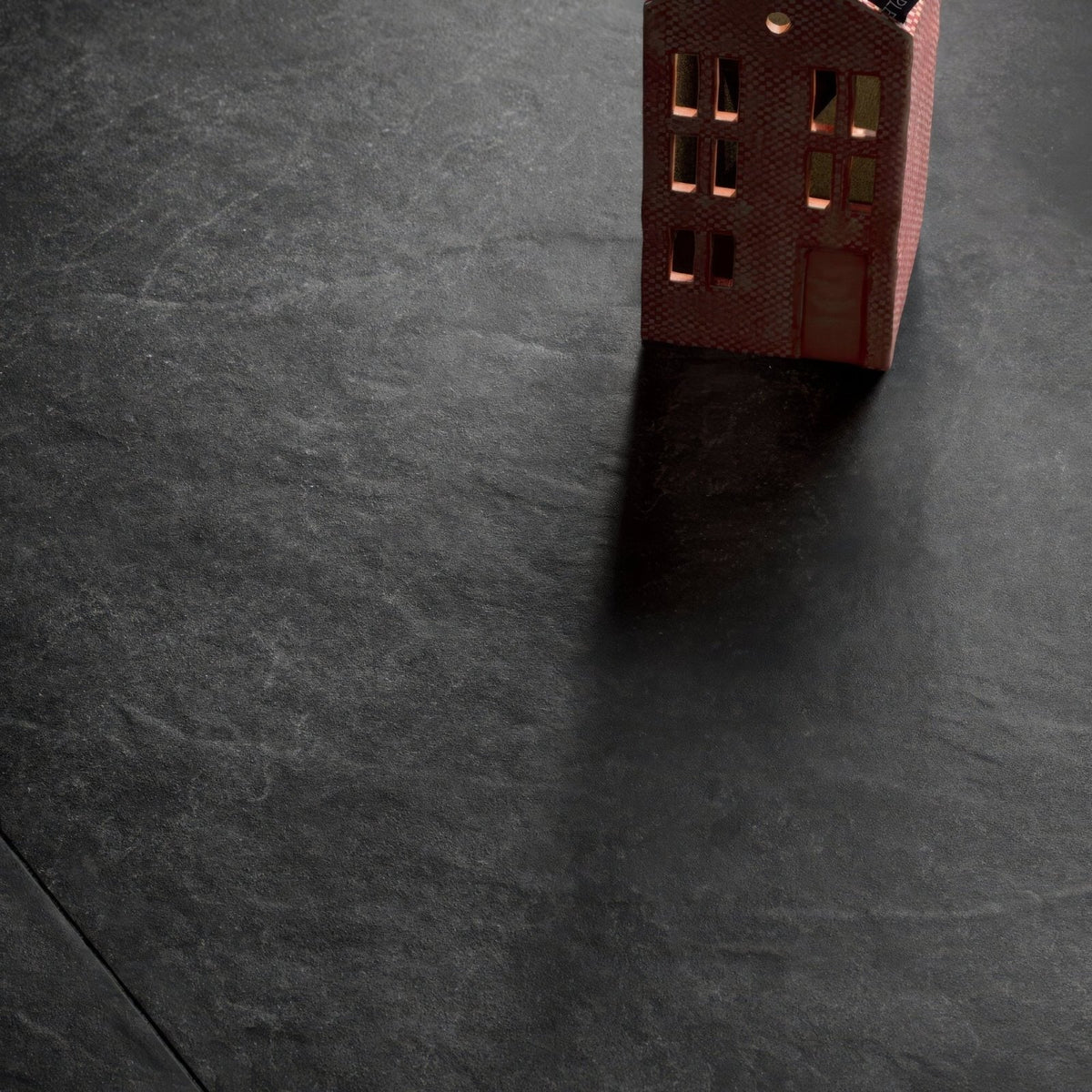 A miniature red brick house model with detailed windows and textured surface showcasing shale black 60 x 120cm tile