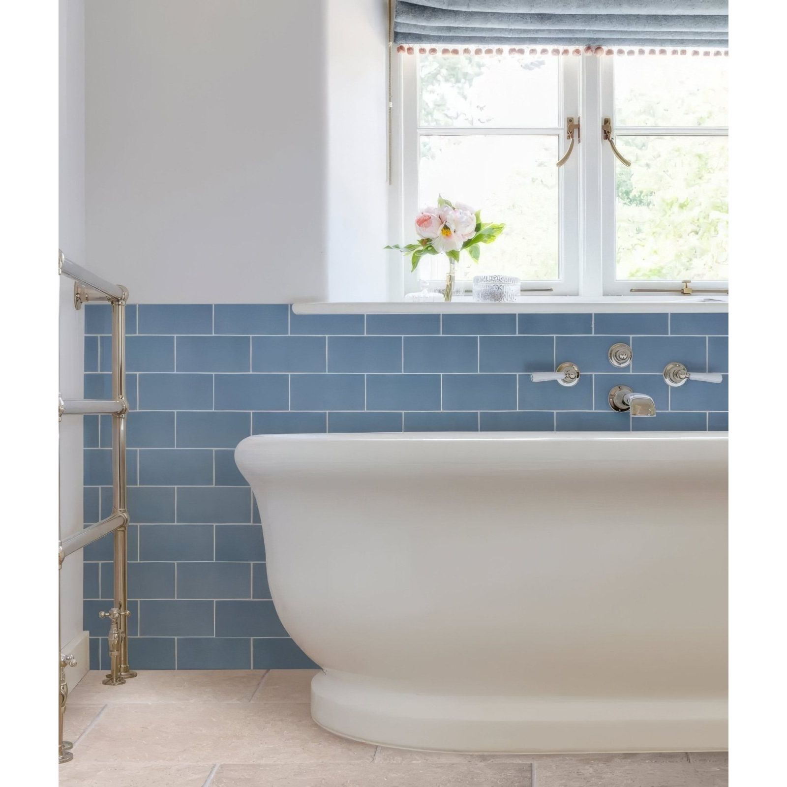 A classic white ceramic clawfoot bathtub with a smooth curved design against blue subway tiles