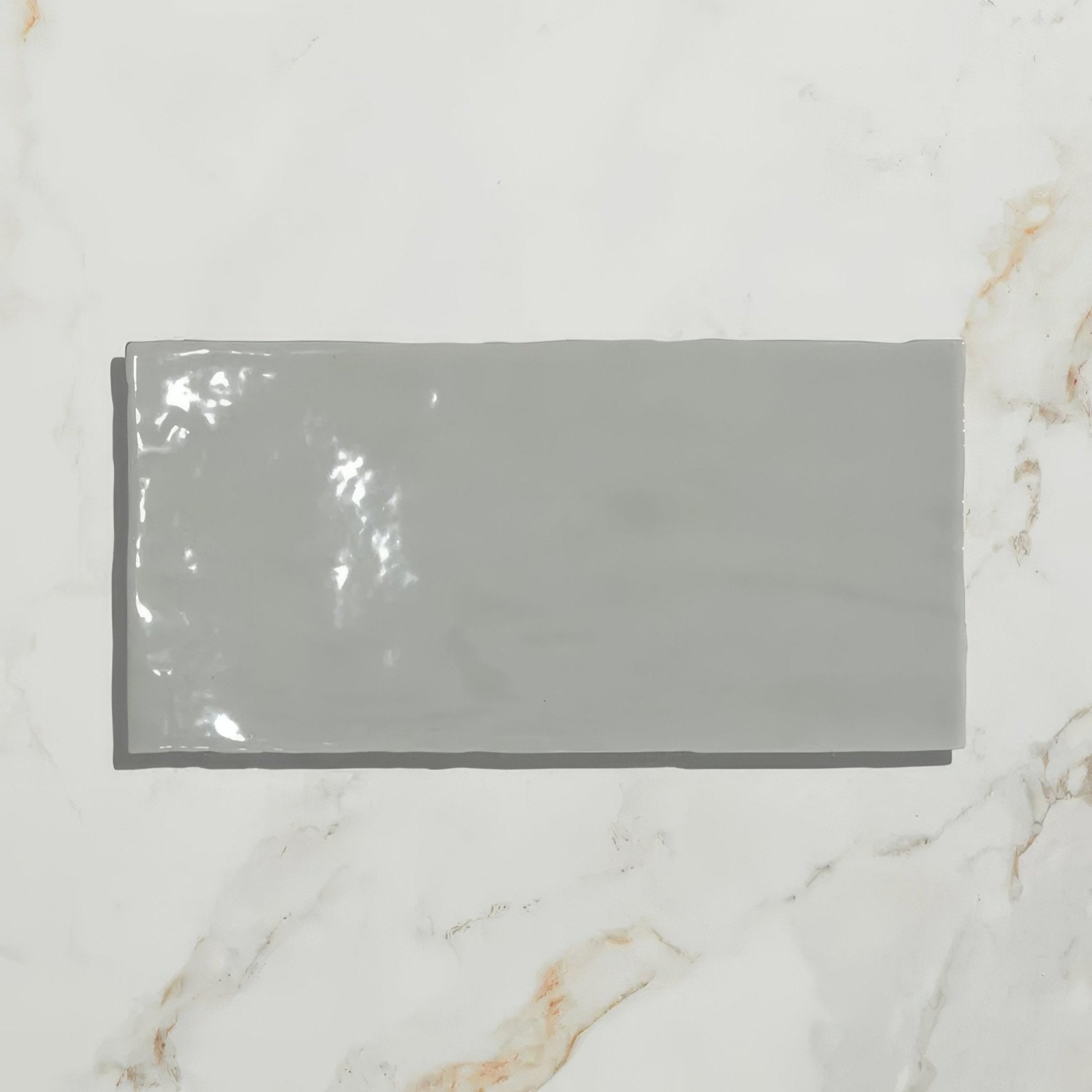 A sleek glossy gray Shoreline ceramic shingle tile with a smooth reflective surface for roofing or siding