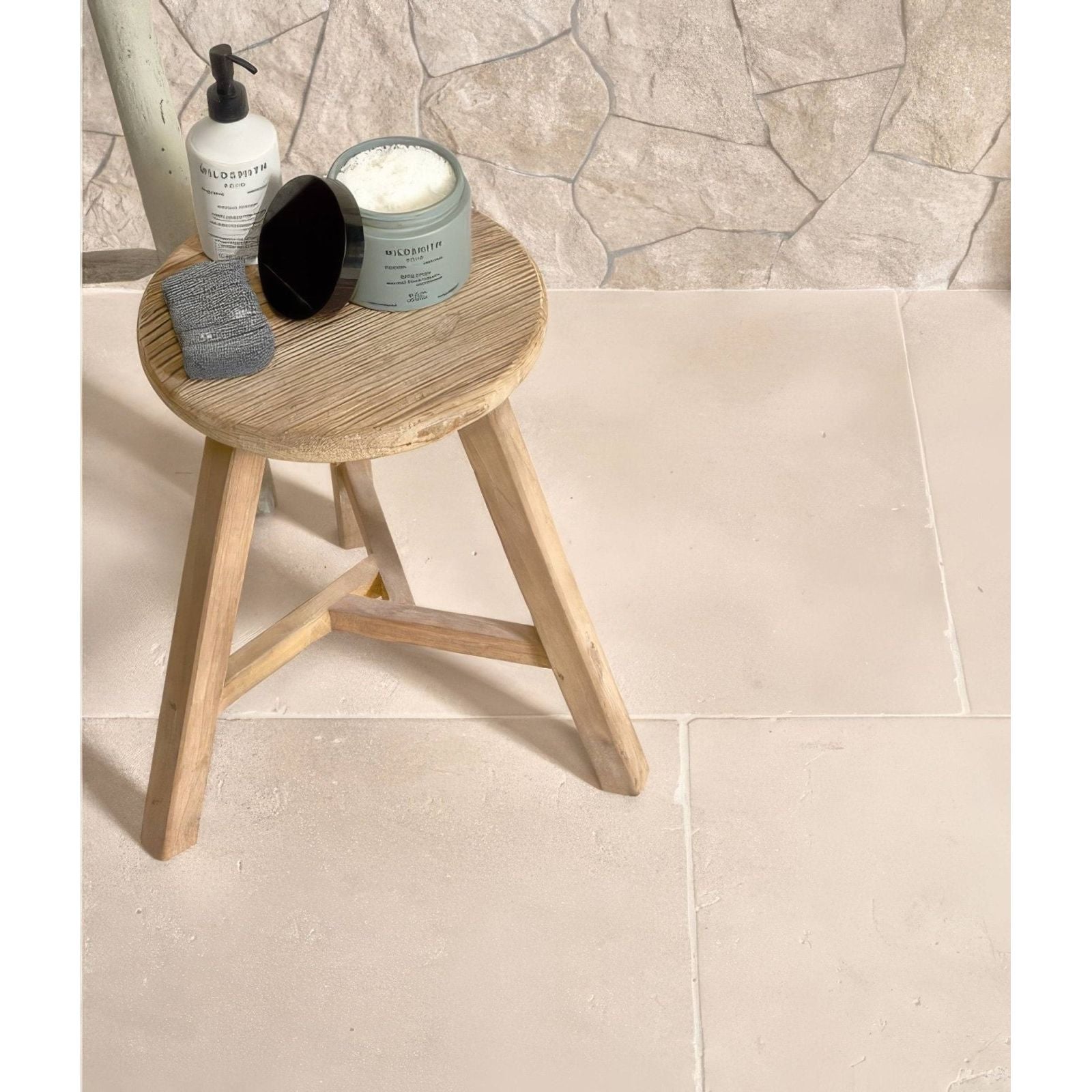 Light wood round stool with three angled legs and natural grain finish in sierra porcelain textured style