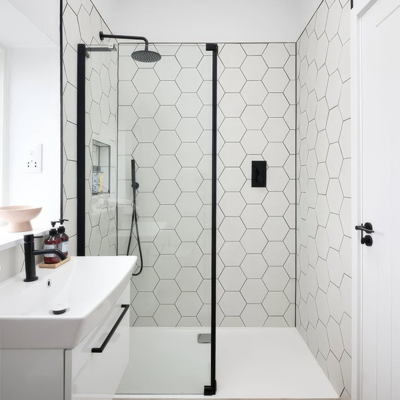 Modern black-framed glass shower enclosure with white hexagonal Signature Porcelain Pearl White tiles and minimalist design