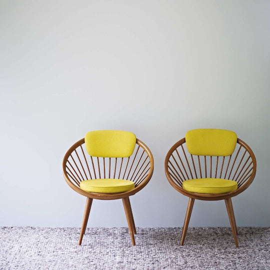 Two vibrant yellow upholstered skylon grey chairs with circular wooden frames and radial spindles