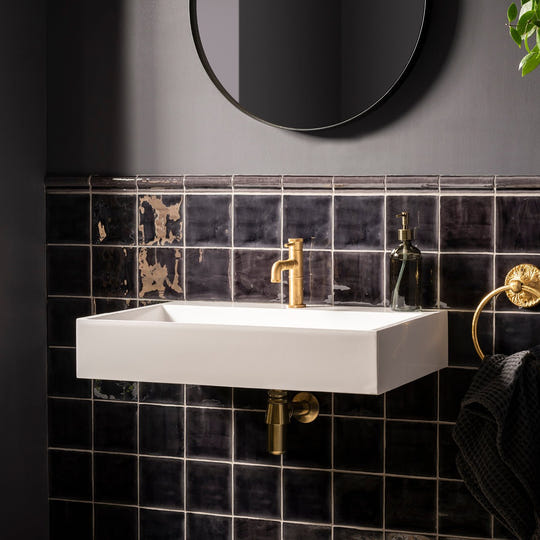 White rectangular wall-mounted sink with gold faucet and matching plumbing featured with sloe field tile background