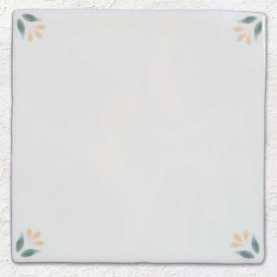 White ceramic tile 13 x 13cm with delicate green and yellow leaf motifs at each corner spring april primrose design