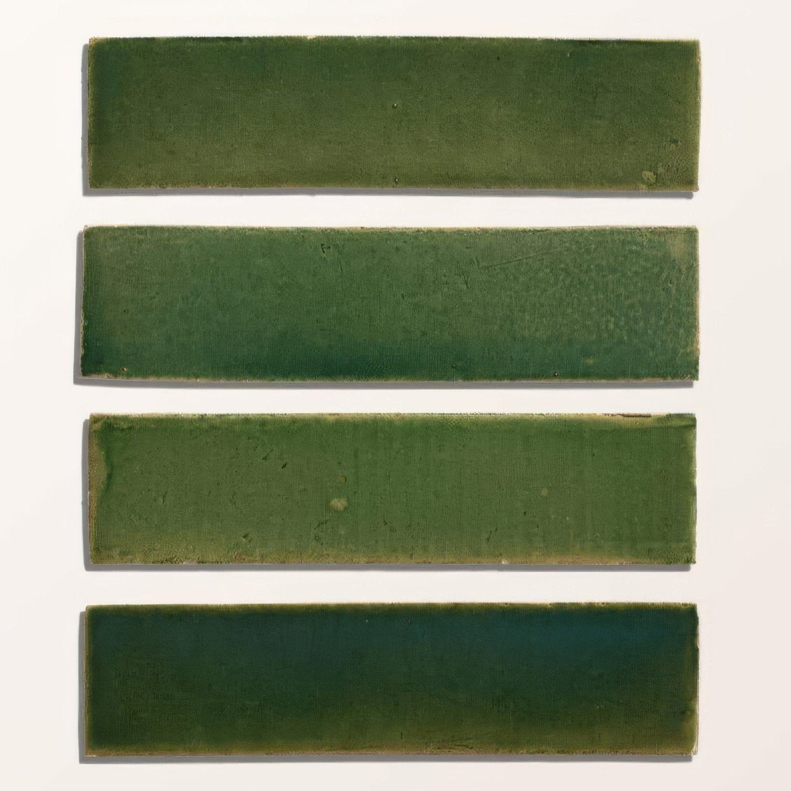 Four rectangular green ceramic tiles with matte finish showing subtle olive to deep forest shades from stone glaze ceramic british green gloss brick