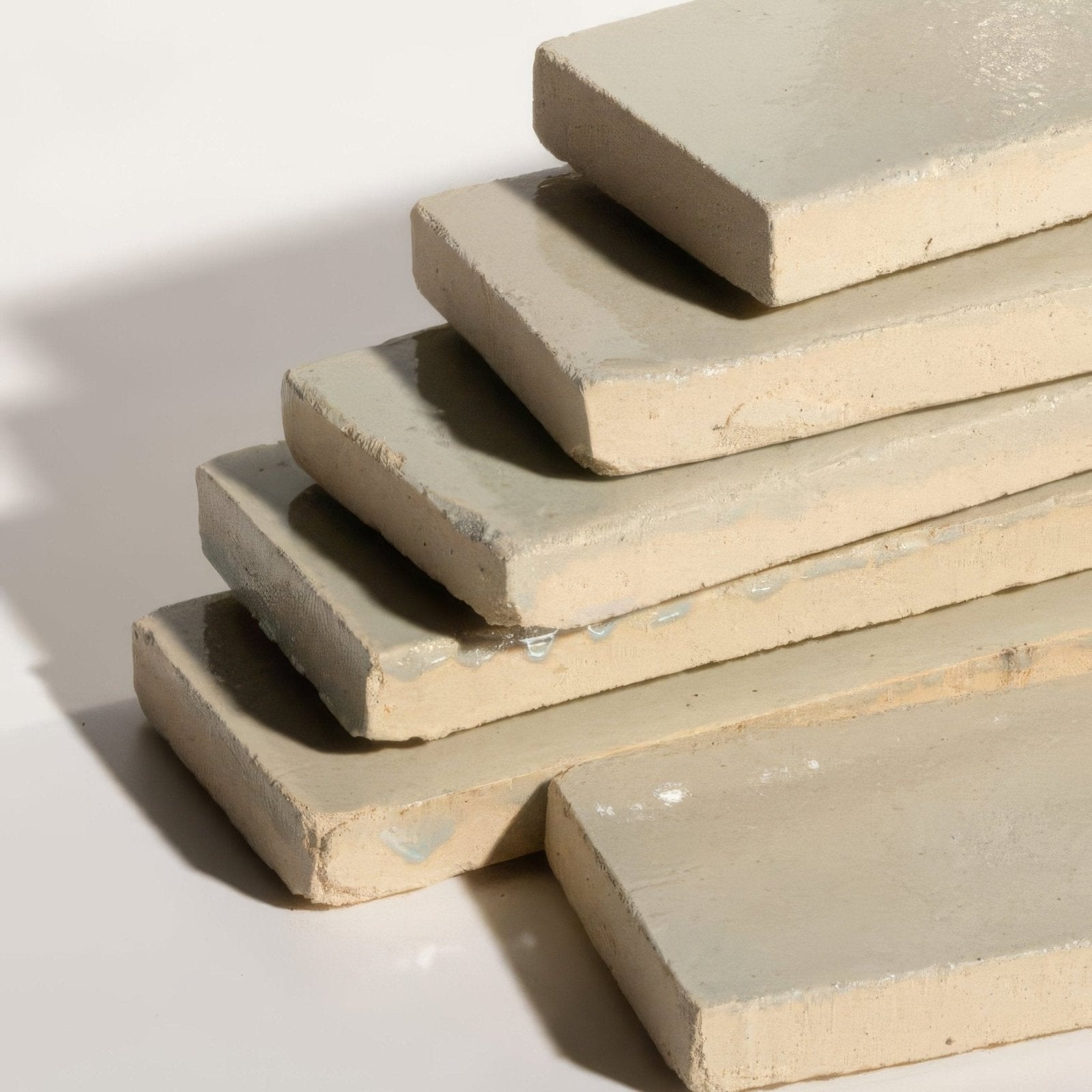Stack of beige stone glaze ceramic chambray gloss brick tiles with matte finished rough edges and subtle texture