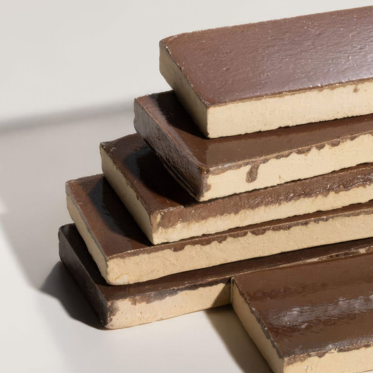 Stacked stone glaze ceramic cola gloss brick with smooth dark brown surface and creamy beige interior layers