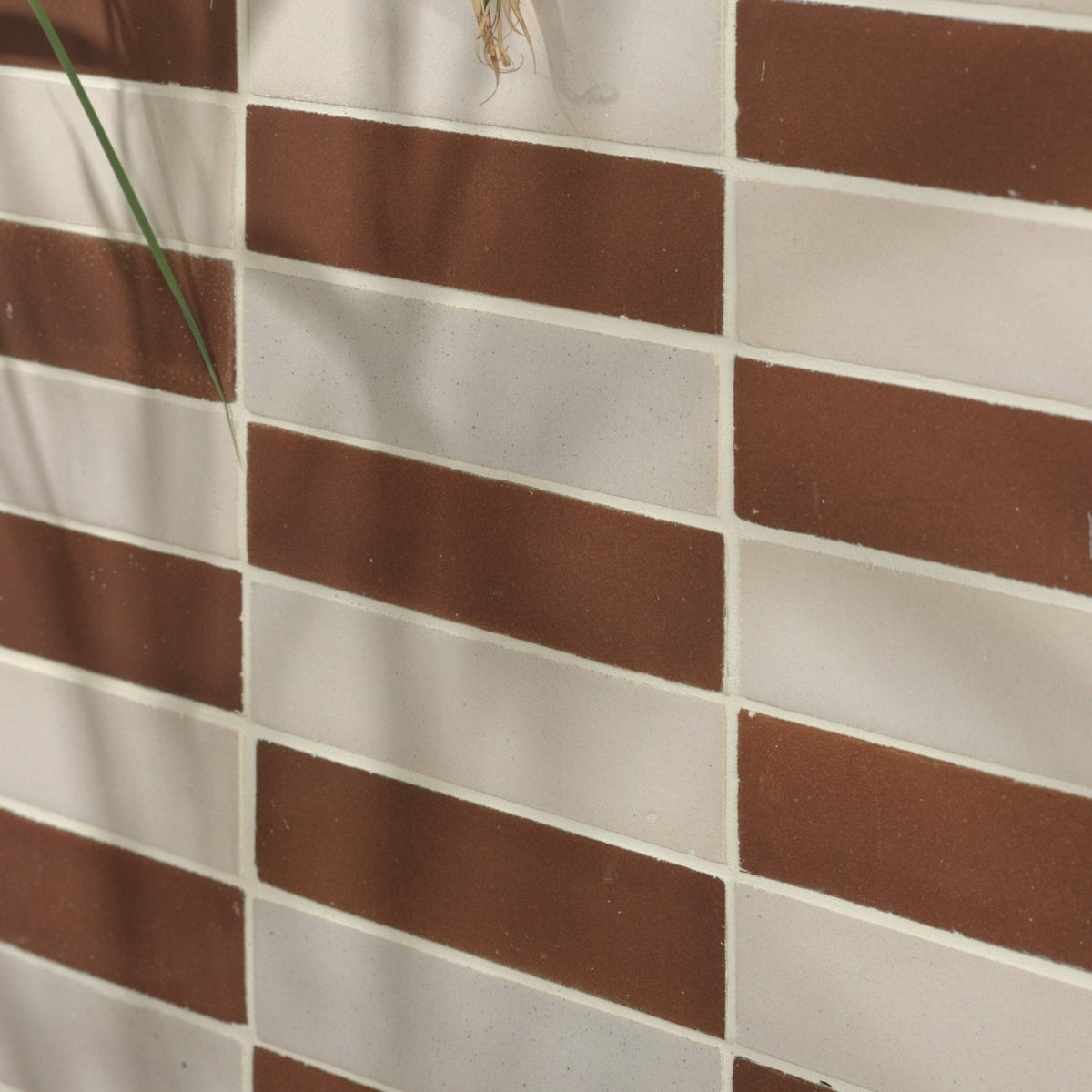 Brown and white rectangular stone glaze ceramic cola gloss brick tiles arranged in a staggered pattern