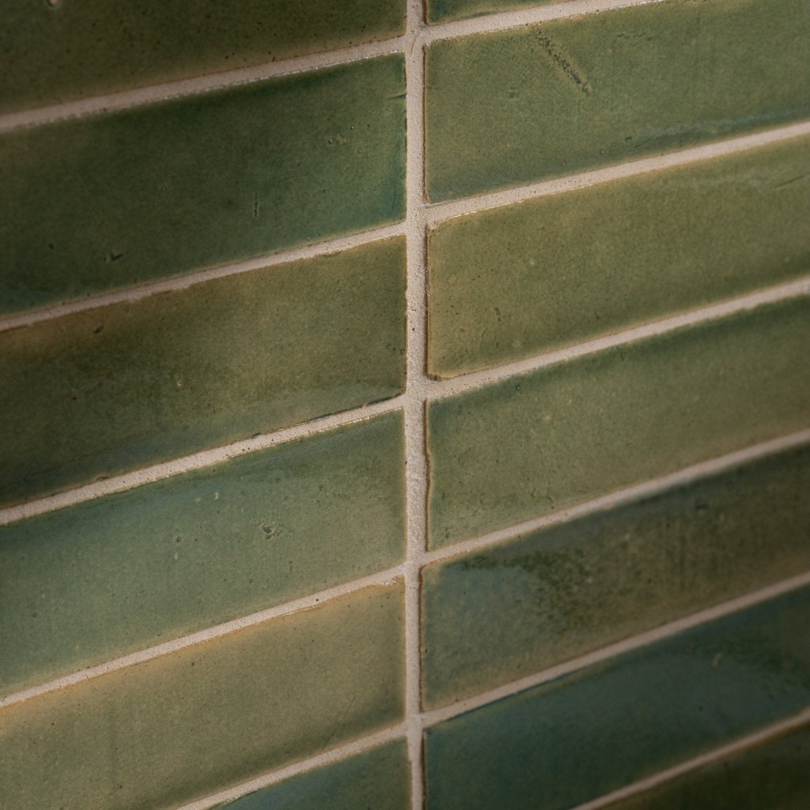 Green rectangular ceramic olive leaf tiles with matte finish and subtle shade variations laid in staggered brick pattern