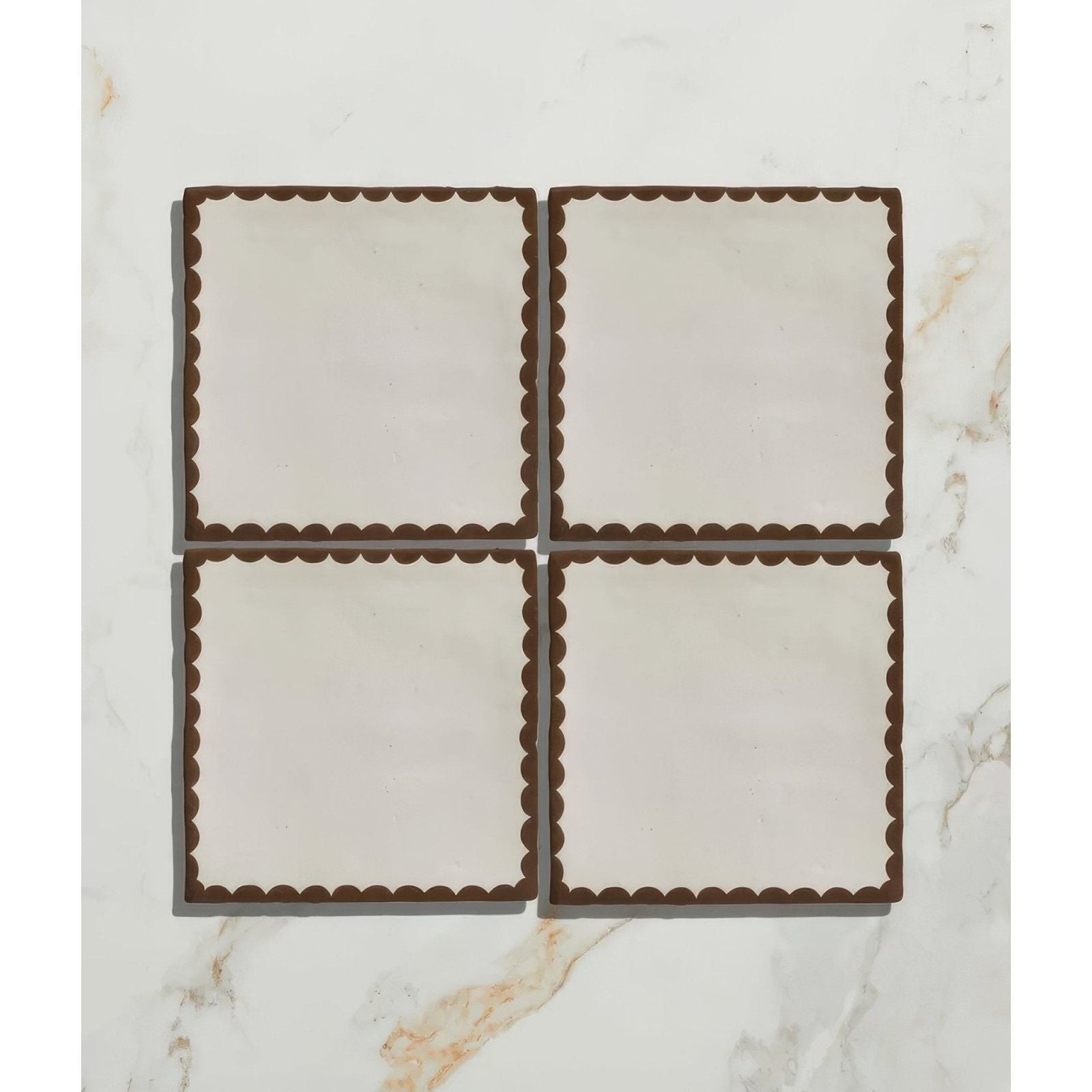 Set of four cream-colored ceramic coasters with dark brown scalloped edges from Studio Bobbin Ceramic Chocolate collection