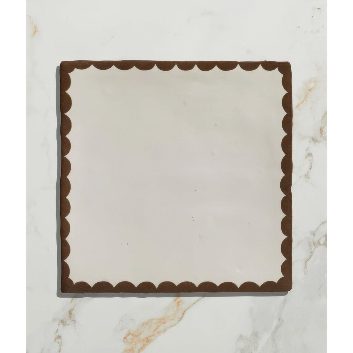 Square ceramic plate by Studio Bobbin with cream center and dark brown scalloped border for serving chocolate